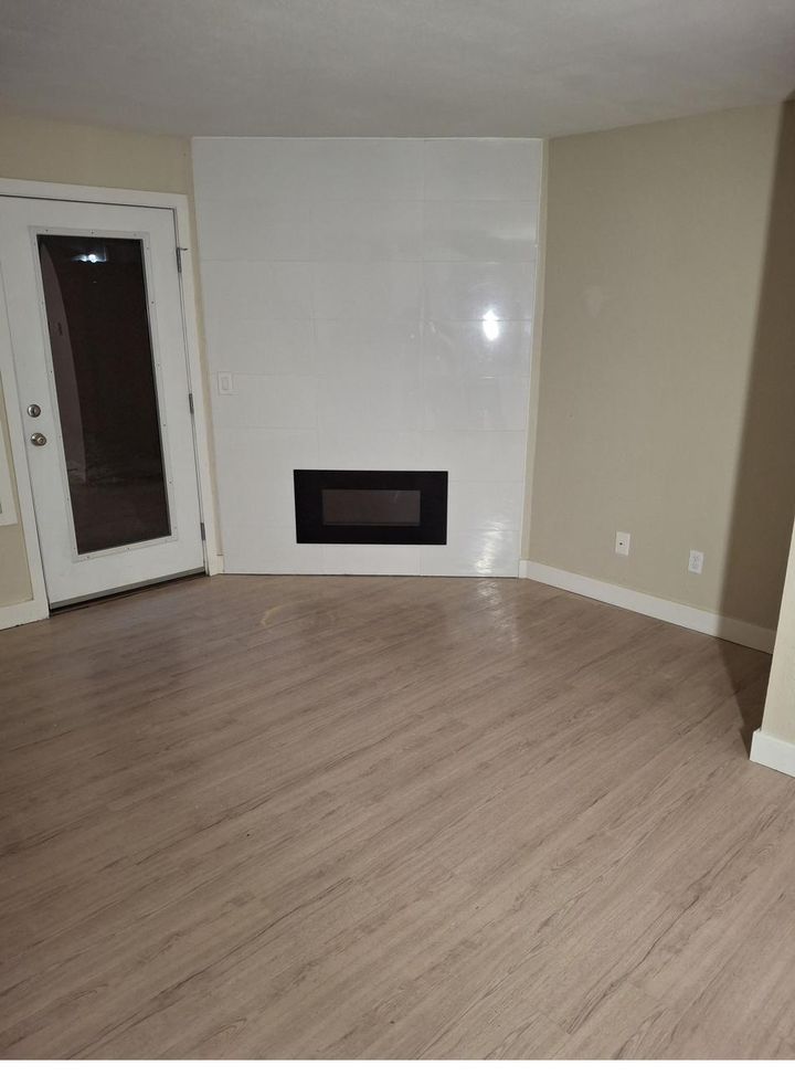 Renovated room with a tiled fireplace and new wood-look flooring
